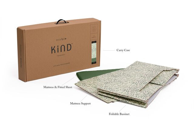 A product image of a foldable Kind Essential Bassinet - Willow Boughs by DockATot that includes a Sorona foam core mattress support and a fitted sheet, all placed next to its packaging box labeled &quot;eco kind bass&quot;.